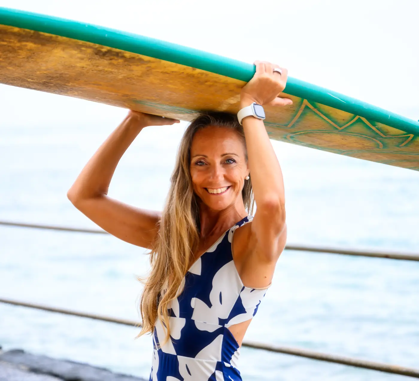 Where structure Chiara Bonvini carrying her surfboard by the ocean in Hawaii